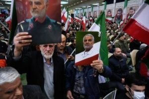 Two men hold up posters of the late commander of Iran's Revolutionary Guard expeditionary Quds Force, Gen. Qassem Soleimani, who was killed in a U.S. drone attack in 2020 in Iraq, during a ceremony commemorating his death anniversary at the Imam Khomeini grand mosque in Tehran, Iran, Thursday, Jan. 1, 2026. (AP Photo/Vahid Salemi)