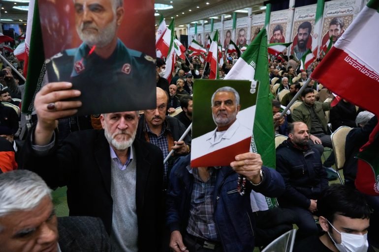 Two men hold up posters of the late commander of Iran's Revolutionary Guard expeditionary Quds Force, Gen. Qassem Soleimani, who was killed in a U.S. drone attack in 2020 in Iraq, during a ceremony commemorating his death anniversary at the Imam Khomeini grand mosque in Tehran, Iran, Thursday, Jan. 1, 2026. (AP Photo/Vahid Salemi)