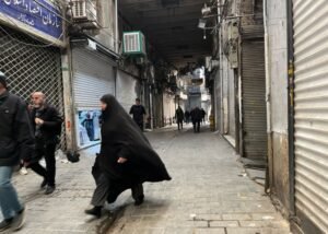 People walk as shops are closed during protests in Tehran's centuries-old main bazaar