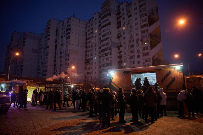 People stand in line for free hot meals that veterans of the 3rd Separate Assault Brigade of Ukraine's Armed Forces serve in residential neighborhood as repeated Russian air attacks on the country's energy sector leave people without power, heating and water in the harshest winter in decades in Kyiv, Ukraine, Sunday, Feb. 8, 2026. (AP Photo/Efrem Lukatsky)