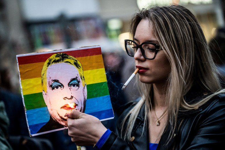 FILE PHOTO: A woman lights a cigarette placed in a placard depicting Hungary's Prime Minister Viktor Orban, during a demonstration, after the Hungarian parliament passed a law that bans LGBTQ+ communities from holding the annual Pride march and allows a broader constraint on freedom of assembly, in Budapest, Hungary, March 25, 2025. REUTERS/Marton Monus/File Photo