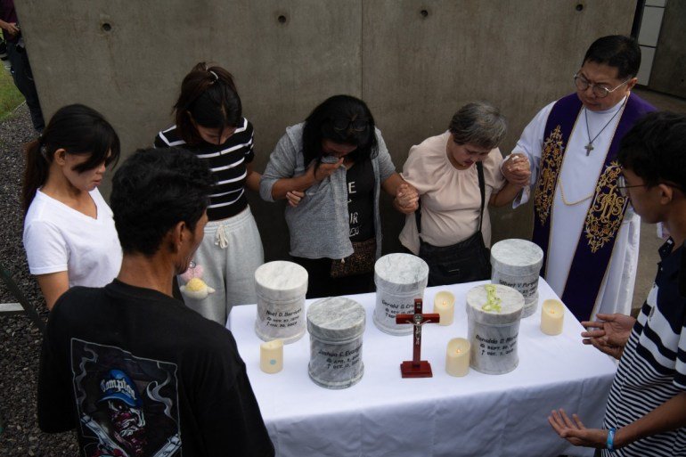 Catholic priest Father Flavie Villanueva (R) joins hands with relatives of extrajudicial killings of former Philippine president Rodrigo Duterte's drug war during the inurnment rites at the "Dambana ng Paghilom" (Shrine of Healing) at a cemetery in Caloocan city, suburban Manila on February 20, 2026.A hearing begins at the International Criminal Court (ICC) on February 23 that will determine whether Duterte will stand trial over at least 76 of those deaths.