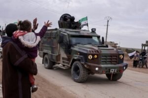 People wave, as internal security forces affiliated with the Syrian government prepare to enter the city of Qamishli in northeastern Syria, following an agreement between Damascus and the Syrian Democratic Forces, in Tel Brak, near al-Hasakah, Syria, February 3, 2026. REUTERS/Khalil Ashawi TPX IMAGES OF THE DAY