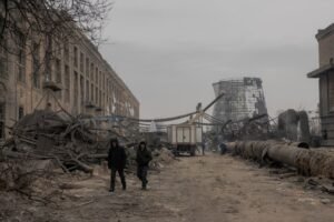 Employees walk past sections of the Darnytska combined heat and power plant damaged by Russian air strikes as they work onn its repair in Kyiv, on February 4, 2026, amid the Russian invasion of Ukraine. Recent Russian strikes on Ukraine's power infrastructure have disrupted light, heating and water supplies to millions across the country as temperatures plummet well below freezing, leaving the war-battered country facing a fresh humanitarian crisis. (Photo by Roman PILIPEY / AFP)