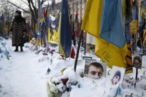 A woman visits the snow-covered memorial for the fallen Ukrainian and foreign fighters on Independence Square in Kyiv on January 13, 2026, amid the Russian invasion of Ukraine. (Photo by Sergei GAPON / AFP)
