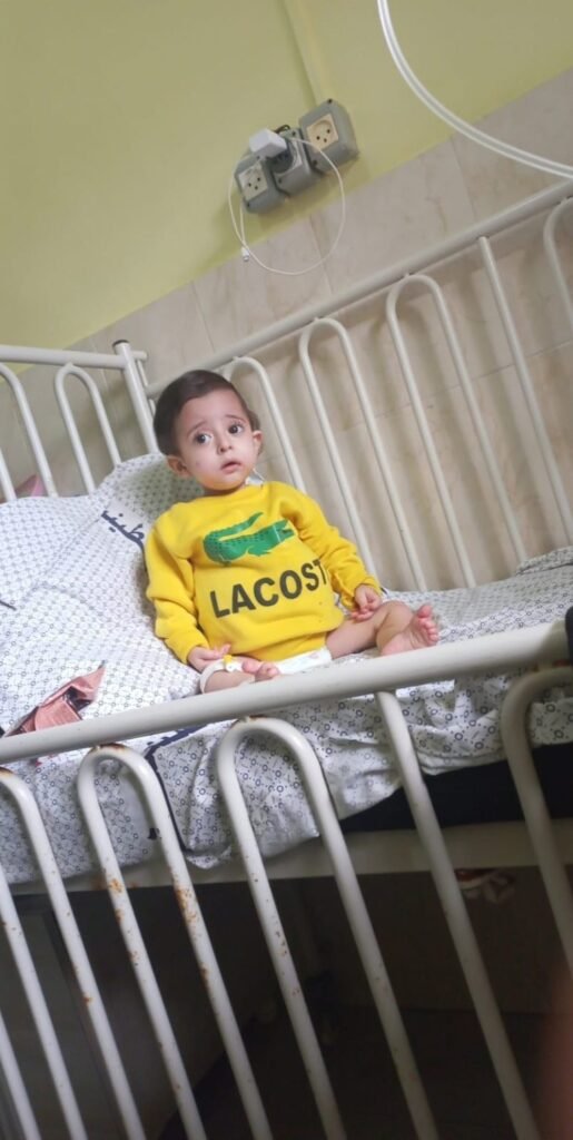 A baby boy sitting in a hospital bed